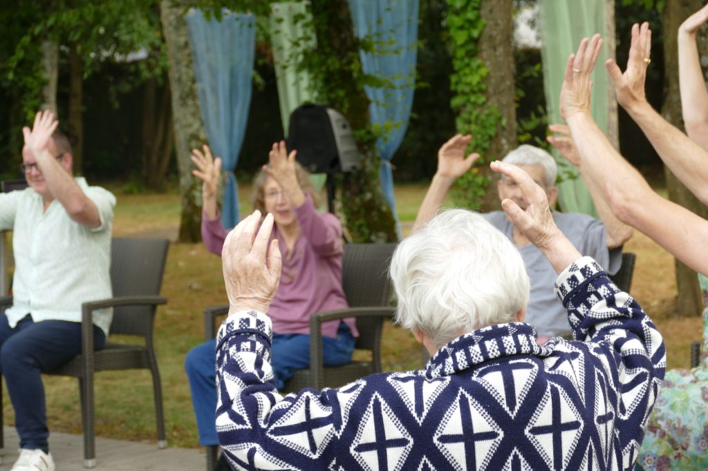 personnes-agees-assises-qui-levent-leurs-mains